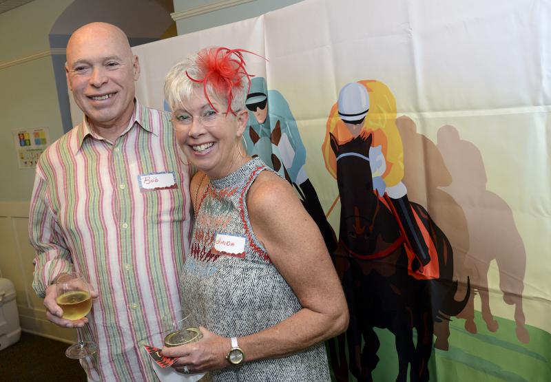 Bob and Linda Gibson pose in the path of an illustrated horse race.